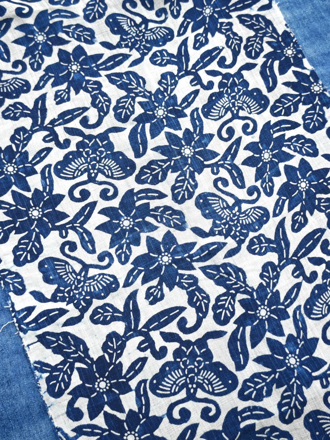 Wider repeat showing butterflies, flowers, leaves and scrolling stems in blue and white.