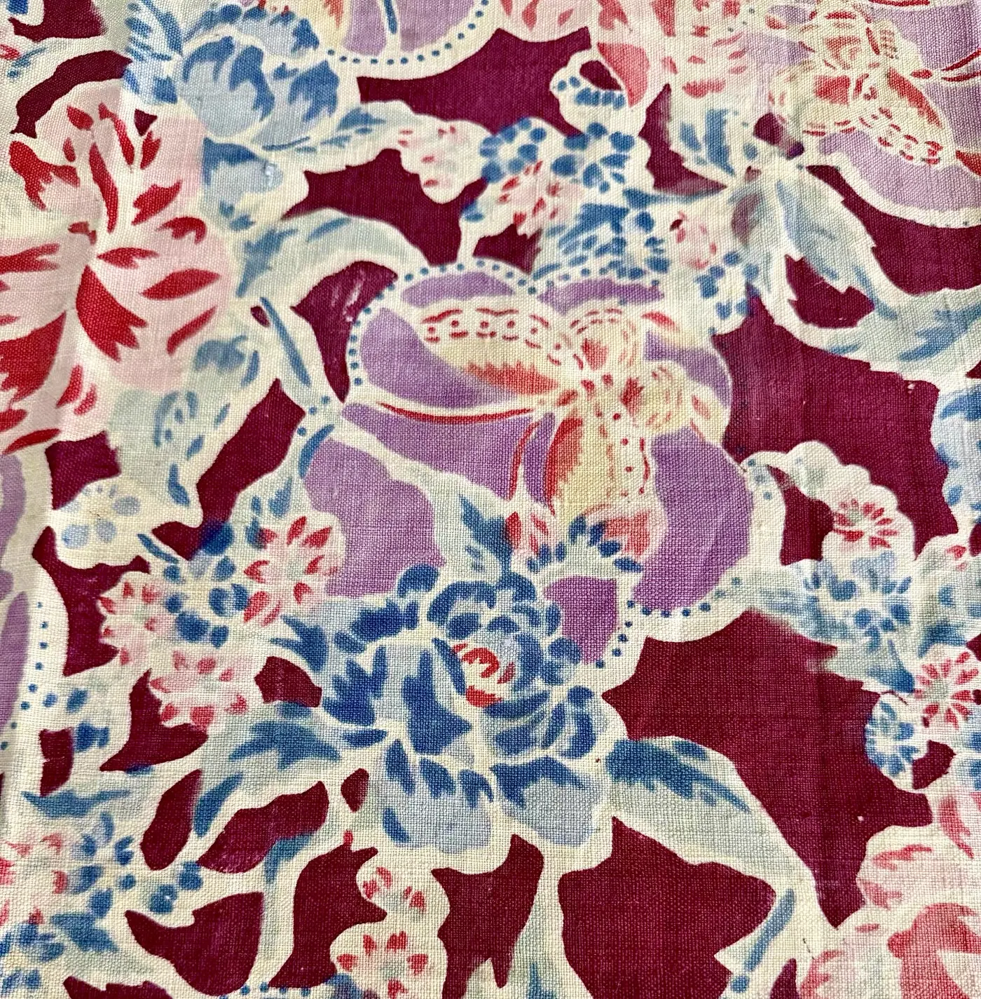 Collected multicolour floral study fragment with pale blue and pink printing on a dark red ground.