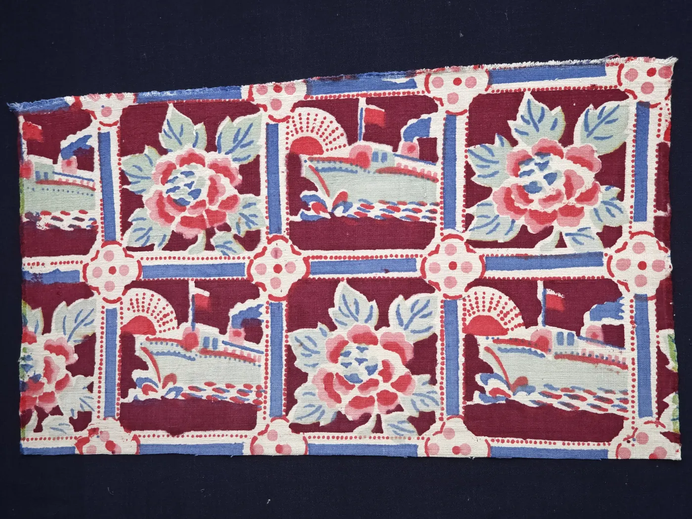 Burgundy-ground repeat alternating pale green architectural forms and peony-like flowers.
