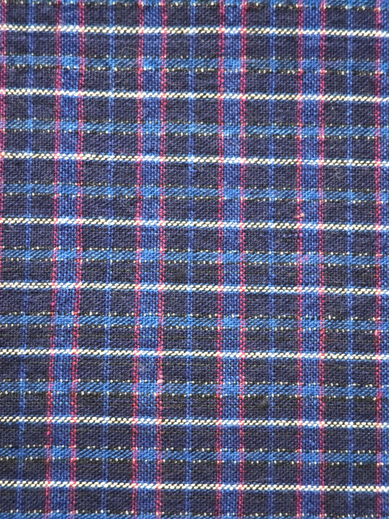 Close view of one red, ivory and blue checked section; this is one part of the changing textile.