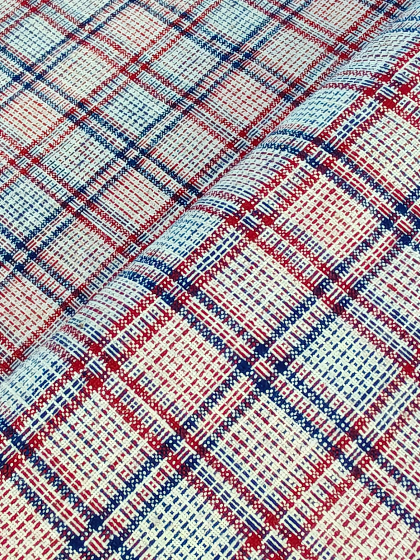 Red and indigo grid with fine comb-like inner lines, photographed close to the cloth.