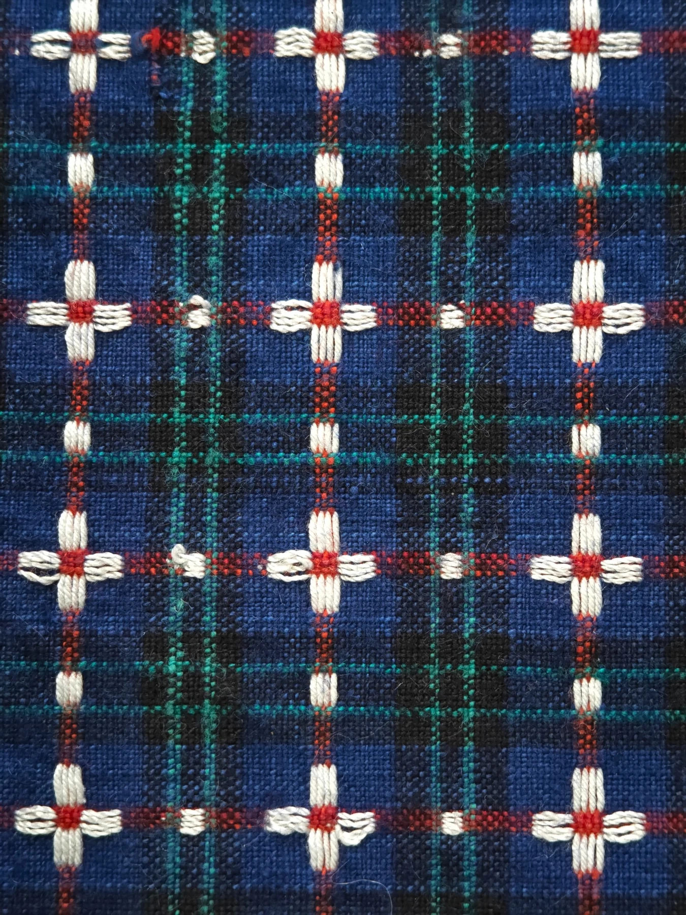 Straight-on detail showing repeated white four-petal flowers across the blue checked ground.